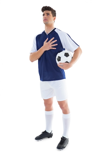 Jogador de futebol em azul de pé com a bola