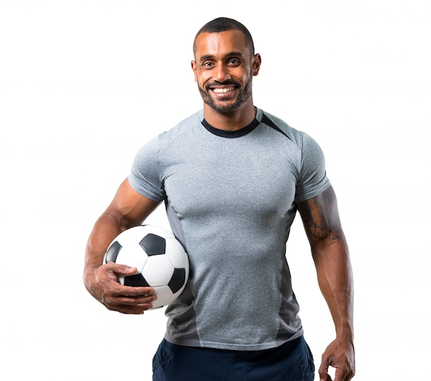 Jogador de futebol forte com bola de futebol e sorrindo em fundo branco  isolado