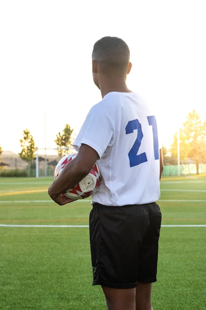 Jogador de futebol hispânico em campo segurando a bola nas mãos