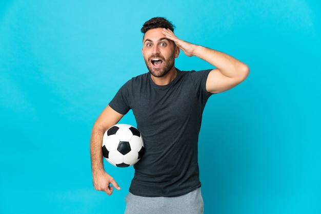 Jogador de futebol isolado em fundo azul com expressão surpresa