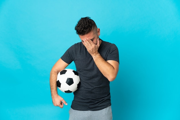 Jogador de futebol isolado em um fundo azul com expressão cansada e doente