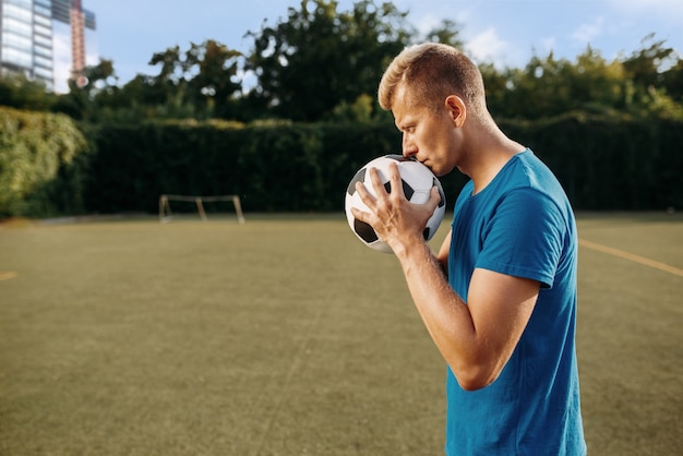 Foto jogador de futebol masculino com bola nas mãos no campo. jogador de futebol no estádio ao ar livre, treino antes do jogo, treino de futebol