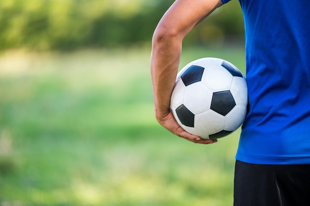 Jogador de futebol, segurando uma bola de futebol