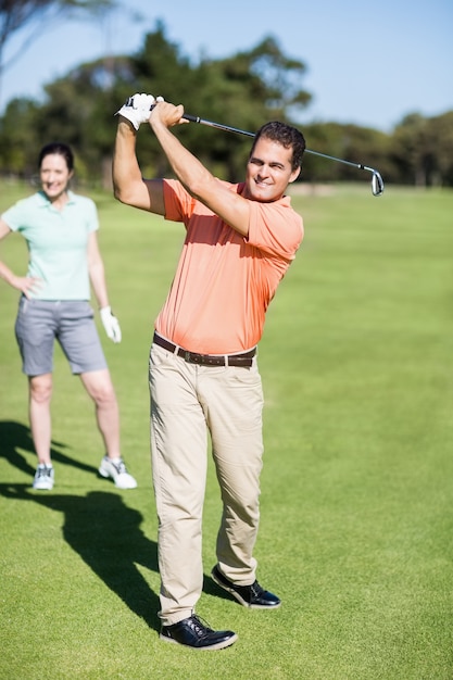 Jogador de golfe alegre que toma o tiro