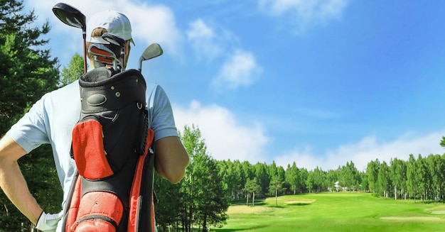 Jogador de golfe andando e carregando a bolsa no curso durante o jogo de verão