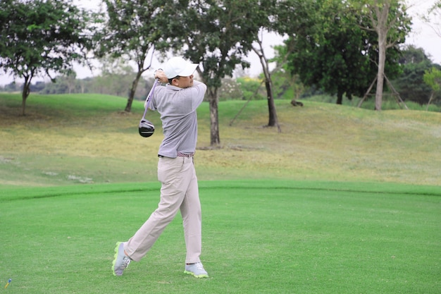 Jogador de golfe asiático teeing fora da bola de golfe da caixa de tee