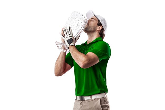 Jogador de golfe com uma camisa verde comemorando com um troféu de vidro nas mãos, sobre um fundo branco.