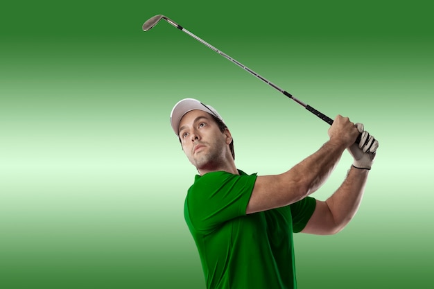 Jogador de golfe com uma camisa verde dando um golpe, sobre um fundo verde.