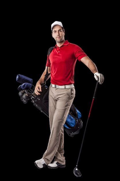 Foto jogador de golfe com uma camisa vermelha, em pé com um saco de tacos de golfe nas costas, sobre um fundo preto.
