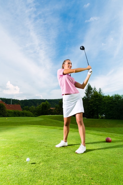 Jogador de golfe feminino jovem em curso fazendo balanço do golfe