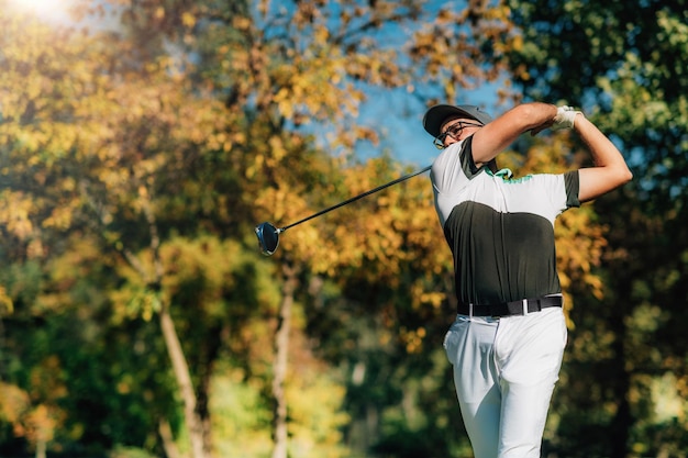 Foto jogador de golfe jogando com o taco de golfe do motorista em um lindo dia de outono