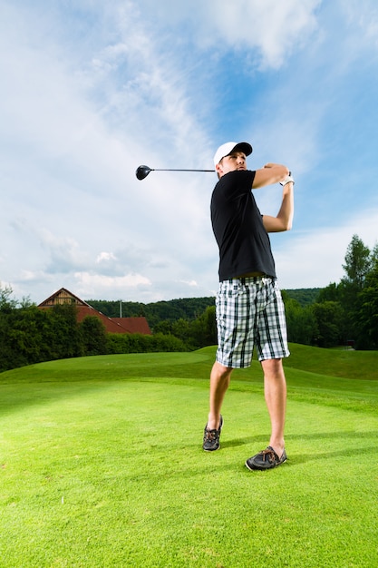 Jogador de golfe jovem em curso, fazendo o balanço do golfe