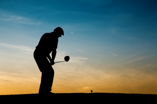 Jogador de golfe masculino sênior ao pôr do sol