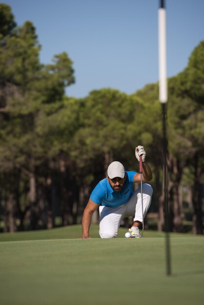 jogador de golfe mirando tiro com taco no curso em lindo dia de sol