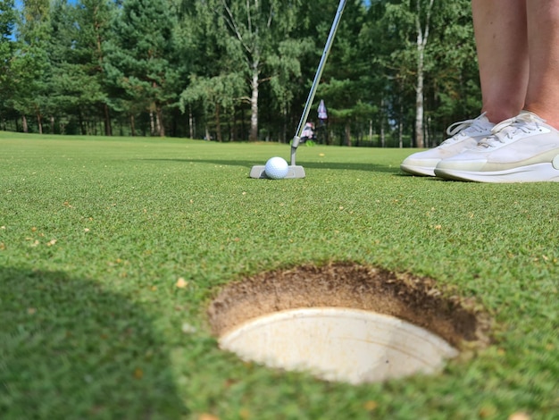 Jogador de golfe no gramado bate a bola no buraco no buraco