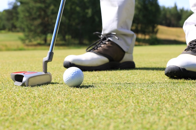 Jogador de golfe no green, batendo a bola em um buraco.