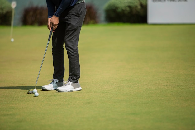 Jogador de golfe no putting green batendo a bola em um buraco