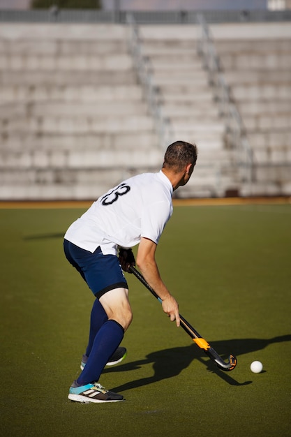 Foto jogador de hóquei em campo treinando e praticando o esporte na grama