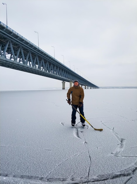 Jogador de hóquei no rio Volga o pano de fundo de uma grande ponte em Ulyanovsk