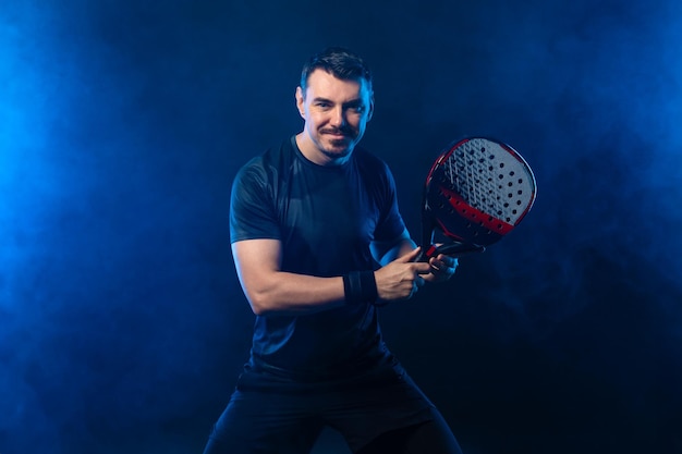 Jogador de padel tennis open tour homem atleta com raquete de padel tenis em fundo preto conceito esportivo