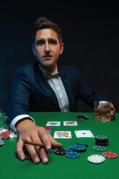 Jogador de pôquer com cartas e fichas na mesa verde no cassino