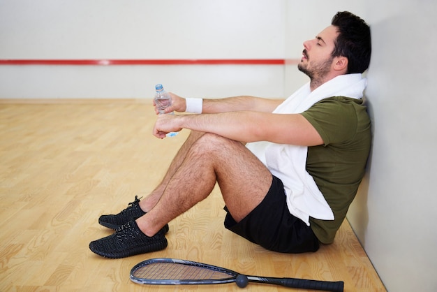 Jogador de squash exausto descansando no chão