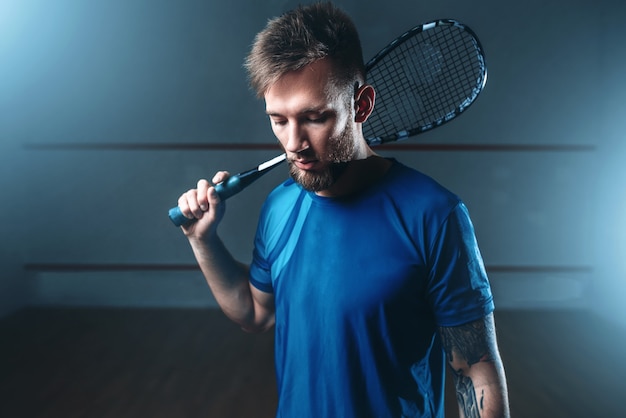 Jogador de squash masculino com raquete, quadra de treinamento coberta