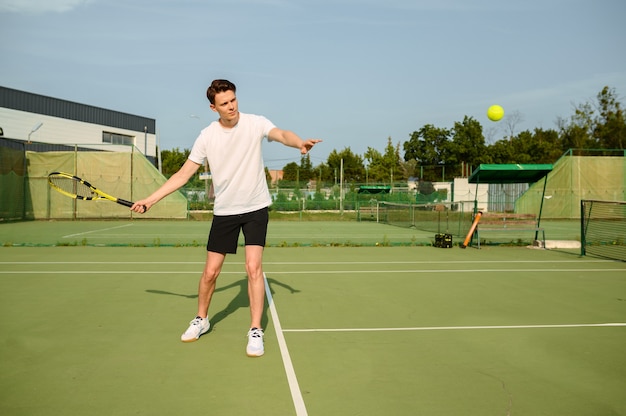 Jogador de tênis com raquete acerta a bola na quadra ao ar livre. Estilo de vida ativo e saudável, competição de jogos esportivos, treinamento físico com raquete