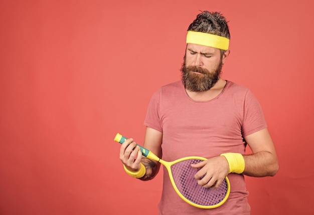 Jogador de tênis moda vintage tênis esporte e entretenimento homem barbudo hipster usar roupa esportiva divertir-se tênis lazer ativo atleta hipster segurar raquete de tênis na mão fundo vermelho