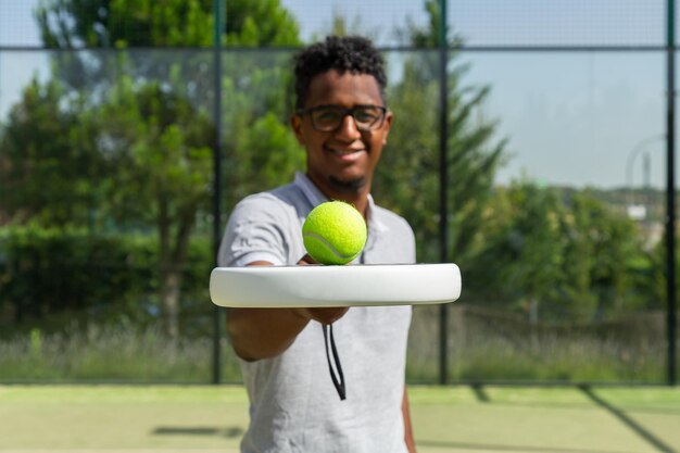 Jogador de tênis preto equilibrando bola na raquete