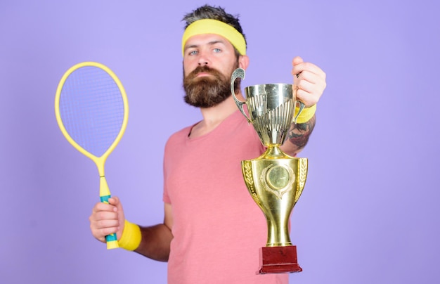 Jogador de tênis vence campeonato Atleta hipster segura raquete de tênis e taça dourada Vença o jogo de tênis Nenhum jogador pode pisar na quadra contra mim e se sentir confiante Hipster barbudo usa roupa esportiva