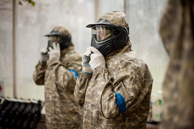 Jogador esportivo de paintball em uniforme protetor e máscara brincando com arma ao ar livre