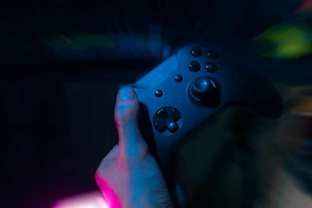 Jogador jogando o jogo online com controlador de joystick em neon glow dark cyberpunk room gaming e esports desafiam streamer de streaming de torneio com dispositivo analógico em casa