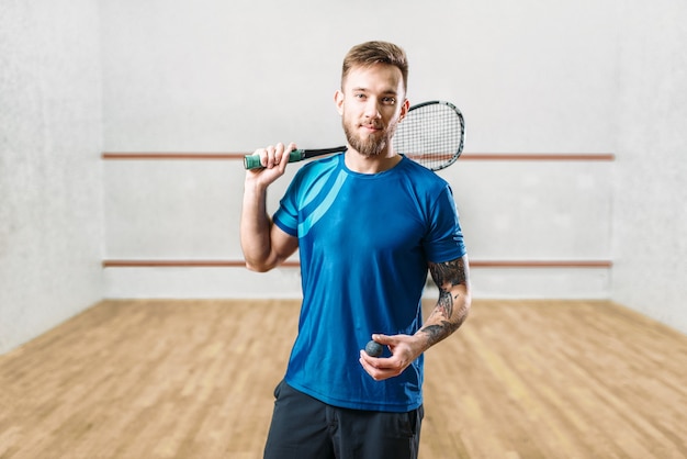 Jogador masculino de squash com raquete e bola nas mãos