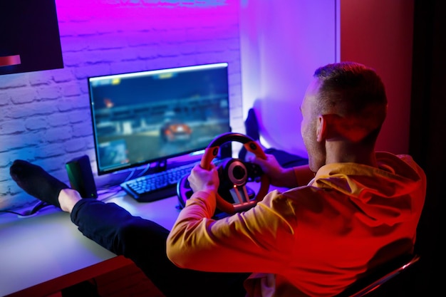 Jogador masculino jogando jogos de corrida no computador Ele usa o volante Jogo emocional