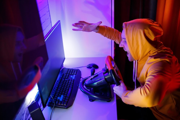 Jogador masculino jogando jogos de corrida no computador Ele usa o volante Jogo emocional