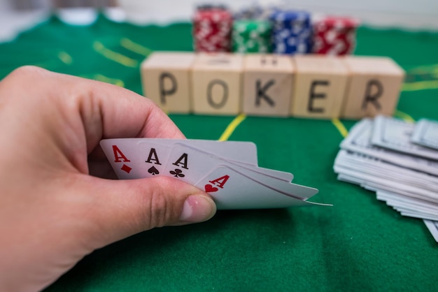 Jogador mostra ases de cartas de jogo em uma mesa verde em um cassino com fichas de jogo