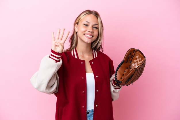 Jogador mulher russa com luva de beisebol isolada em um fundo rosa feliz e contando quatro com os dedos