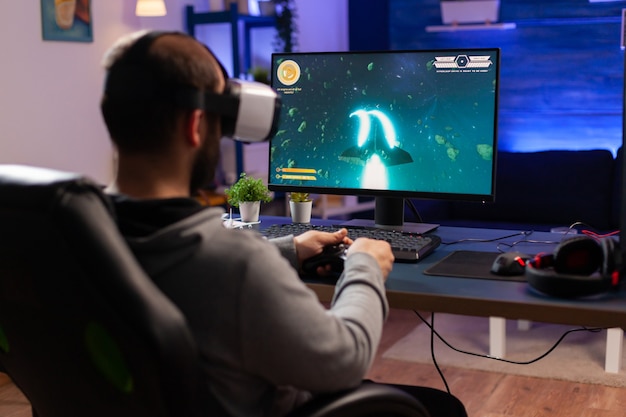 Jogador profissional usando fone de ouvido realilty virtual e jogando videogame de atirador espacial com controlador. homem fazendo streaming de videogames online para torneio esport em uma sala com luzes de néon