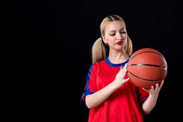 jogadora de basquete com roupas esportivas e bola no fundo preto. Atleta de exercícios de jogo