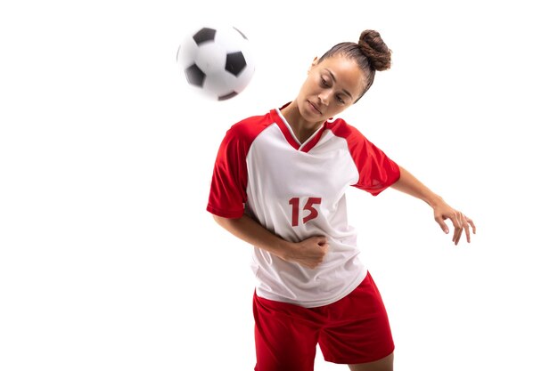 Foto jogadora de futebol jovem biracial batendo uma bola de futebal com o ombro enquanto joga futebol