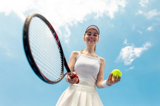 Jogadora de tênis de menina em uniforme segura raquete e bola na quadra de tênis atleta de mulher joga tênis