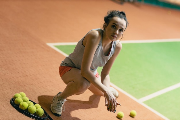 Jogadora de tênis jogando treinamento com raquete e bola na quadra