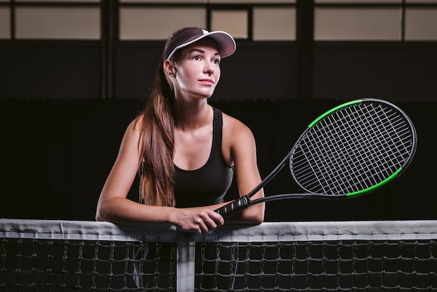 Jogadora segurando uma raquete de tênis pela rede