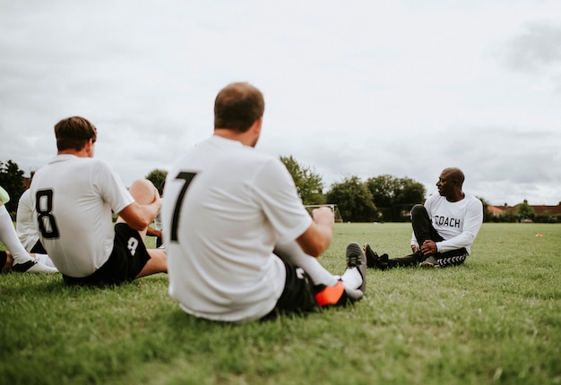 Jogadores de futebol masculino, estendendo-se juntos