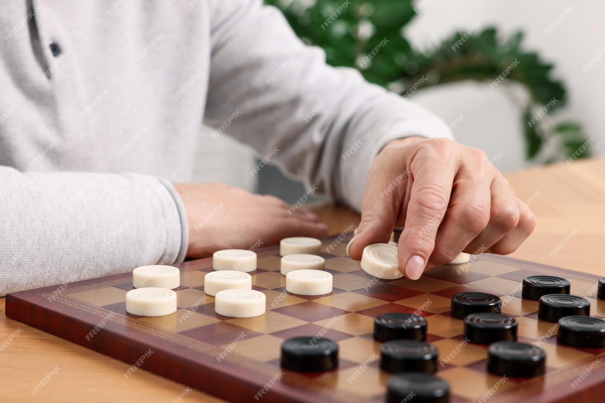 Jogando damas homem sênior pensando sobre o próximo passo na mesa