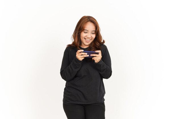 Jogando jogo para celular no smartphone de linda mulher asiática vestindo camisa preta isolada no branco