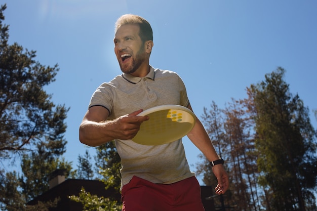 Foto jogando um jogo. homem alegre e atraente sorrindo e brincando ao ar livre