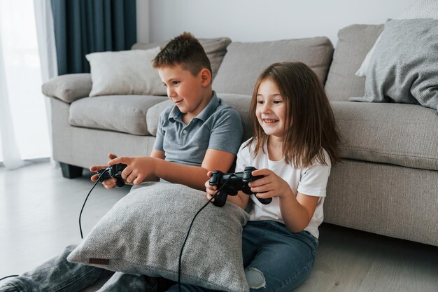 Foto jogando videogame crianças se divertindo na sala doméstica durante o dia juntos