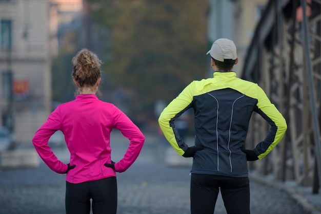 Joggendes Paar, das sich vor dem morgendlichen Laufen in der Stadt aufwärmt und dehnt